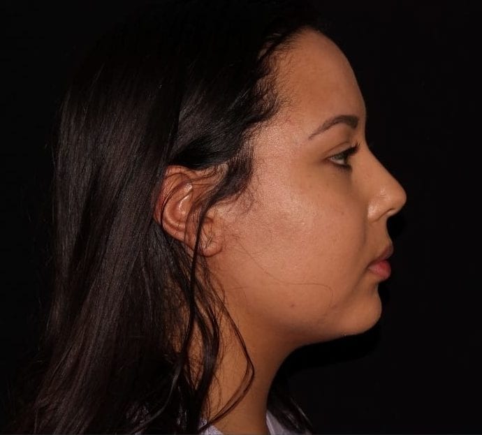 Side profile of a woman with dark hair against a black background, highlighting her facial features in a calm expression.