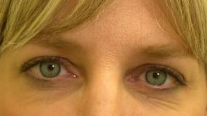 Close-up of a woman's eyes, focusing on her light blue irises and part of her blonde fringe visible at the top.