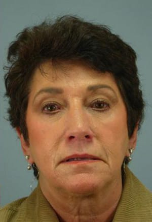 Portrait of a middle-aged woman with short dark hair, wearing a tan blazer and small earrings, looking directly at the camera.