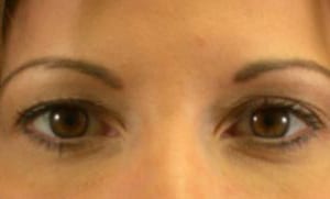 Close-up of a woman's eyes, showing brown irises and neatly shaped eyebrows, cropped to the upper face.