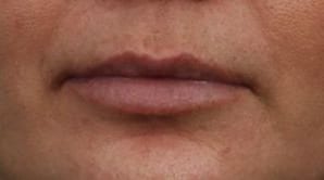 Close-up of a person's closed lips showing detailed texture of the skin. the lips are slightly parted, and the surrounding skin has a natural tone.