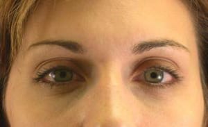 Close-up of a woman's face focusing on her eyes, which are looking directly at the camera. she has light skin and wears minimal makeup.