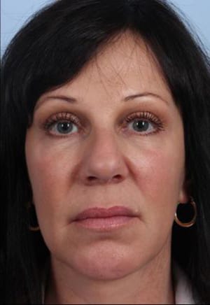 A close-up portrait of a woman with dark hair and fair skin, featuring gold hoop earrings, looking directly at the camera with a neutral expression.