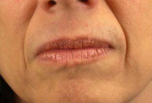 Close-up of a person's closed lips showing natural lip texture and slight wrinkles around the mouth area. the background is out of focus.