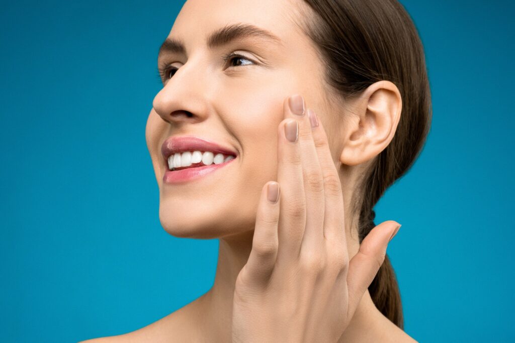 smiling woman touching her cheek after a Neurotoxin injection