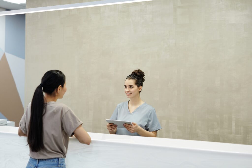 Receptionist smiling at a patient receiving Botox® treatment for TMJ