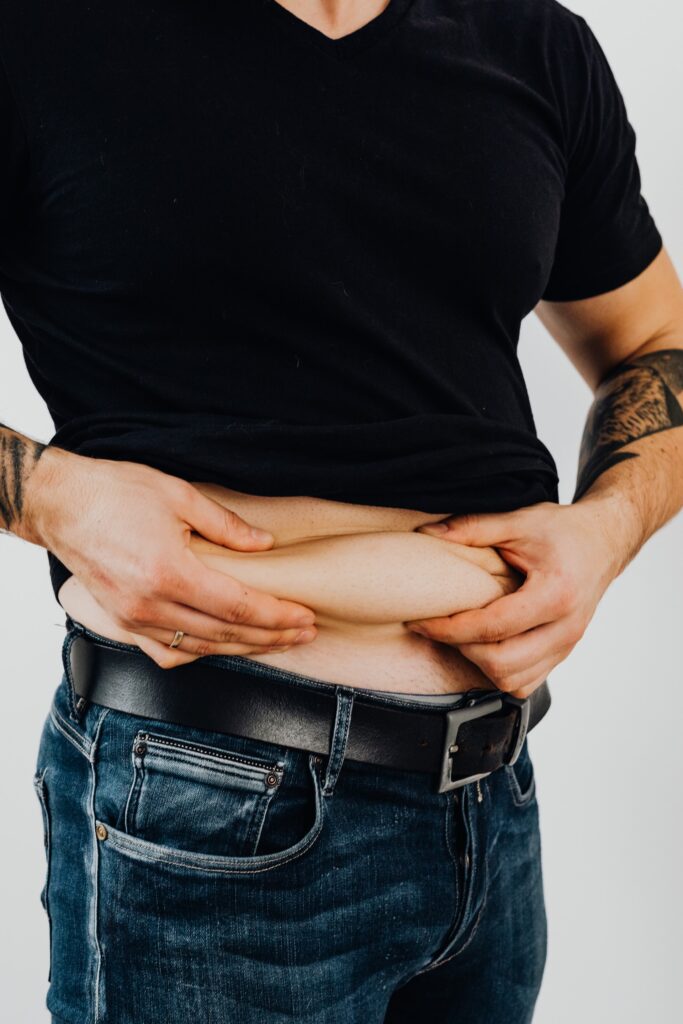 Man with lifted shirt pinching his belly fat