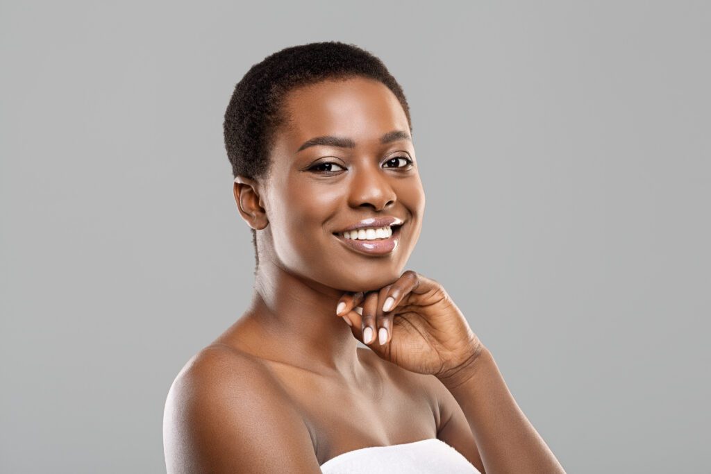 woman with short, brown hair and dark skin resting her chin on her hand while smiling