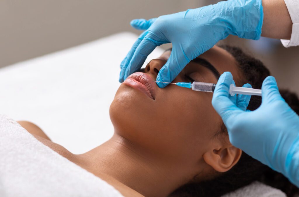 medical professional wearing blue latex gloves administering lip injections with a medical needle