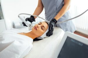 Beautician conducts a microneedling facial rejuvenation procedure for a brunette woman