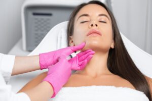 Woman receiving Kybella double chin injection by technician in pink gloves