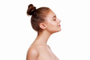 Young Girl with Brown Hair on top, closed Eyes, thick Eyebrows and Naked Shoulders at White Background, copy space, Beauty Photo, close up, Antiaging Concept, Lifting Arrows or Lines on Face