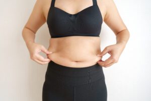 Close up of a women's torso as she pinches excess fat on her sides